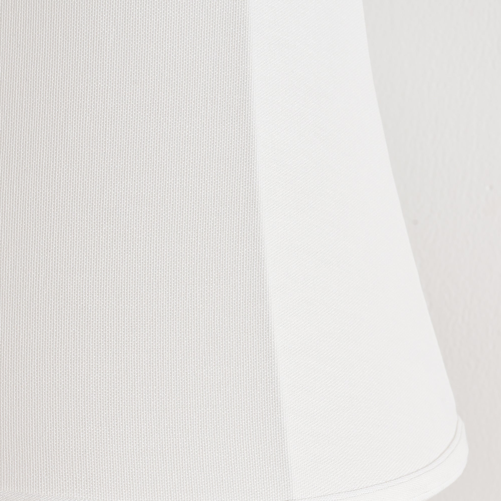 Close-up of a white fabric lampshade with a subtle textured weave