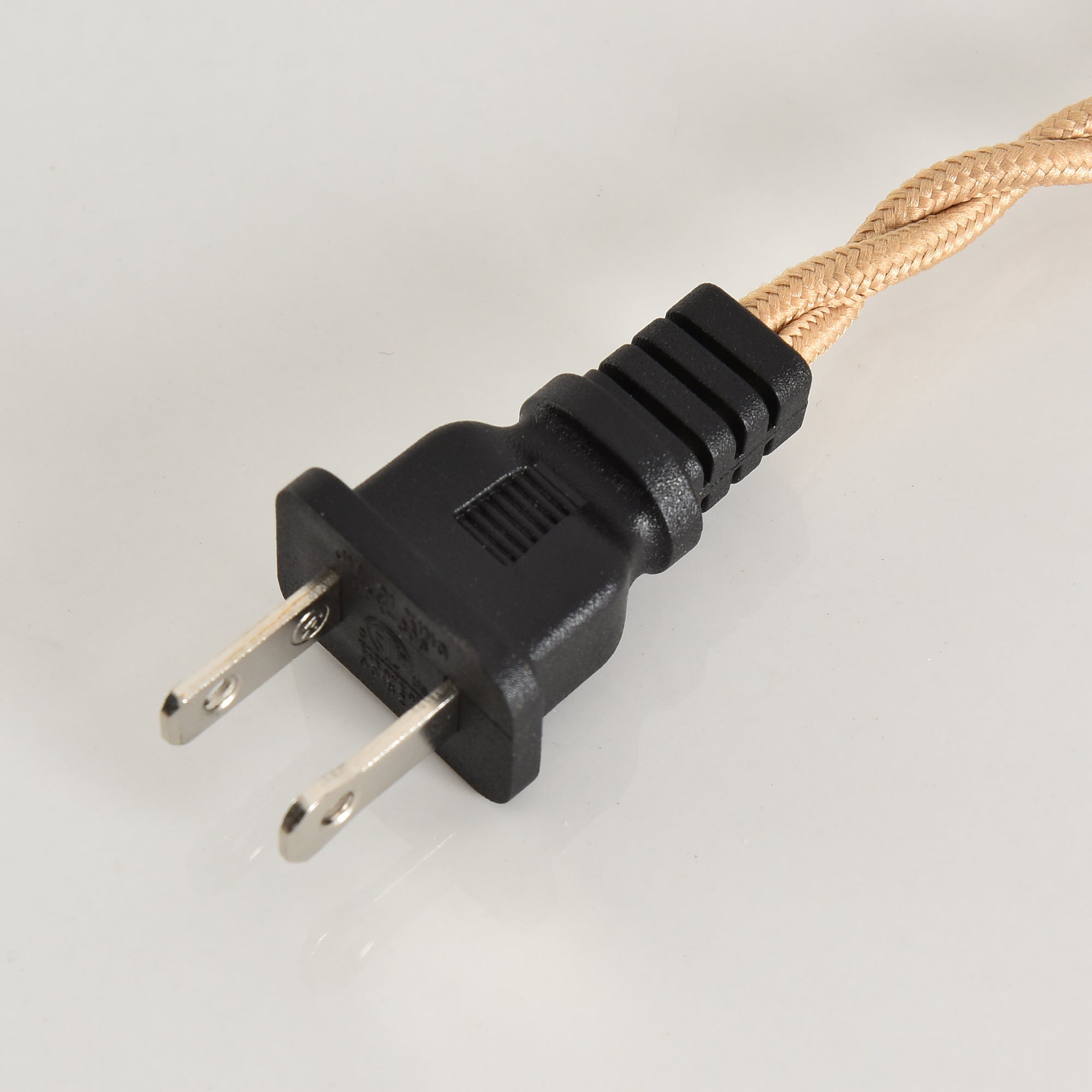 Close-up of a black two-prong power plug with a braided tan fabric cord