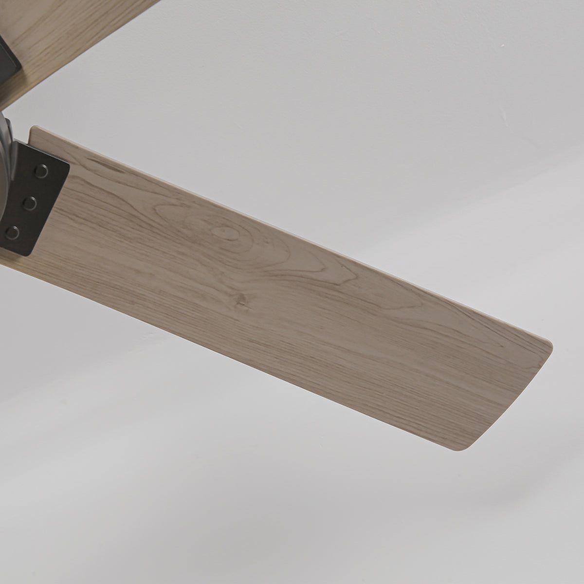 Close-up of a modern ceiling fan blade with a light wood grain finish.