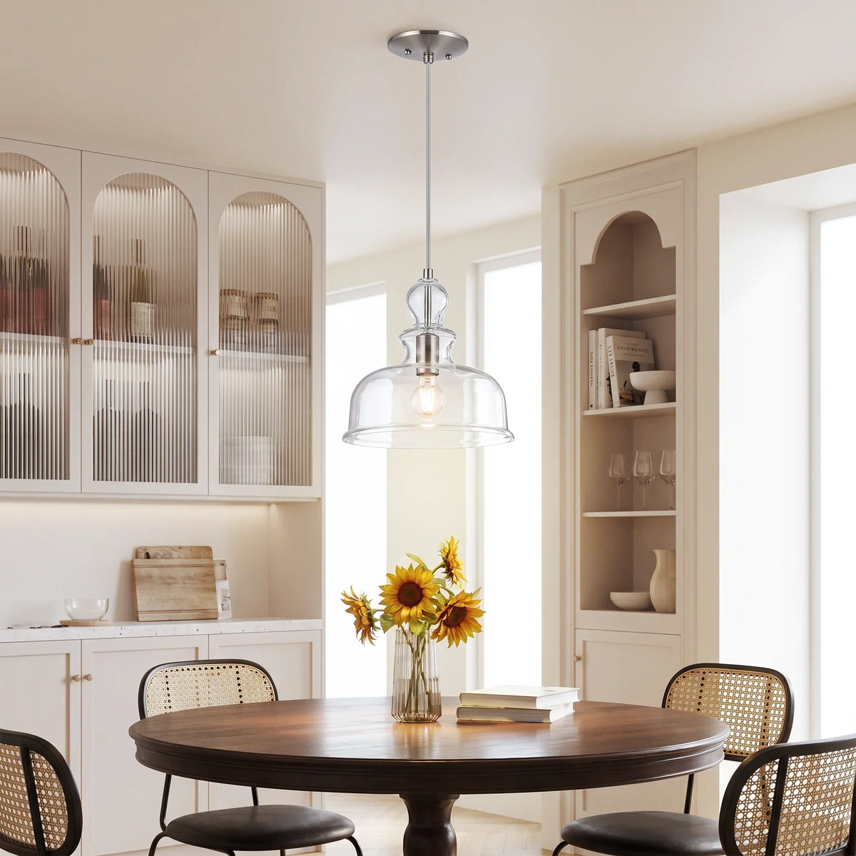 Elegant glass pendant light hanging over a round wooden dining table in a bright kitchen.