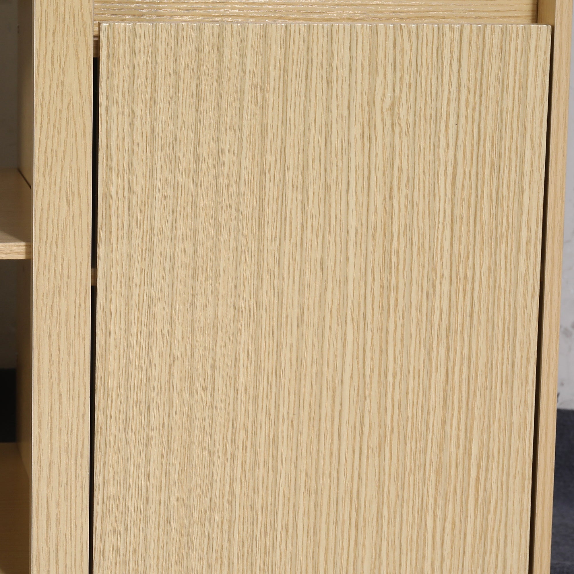 Close-up of a light-colored natural oak wood cabinet door with vertical grain.