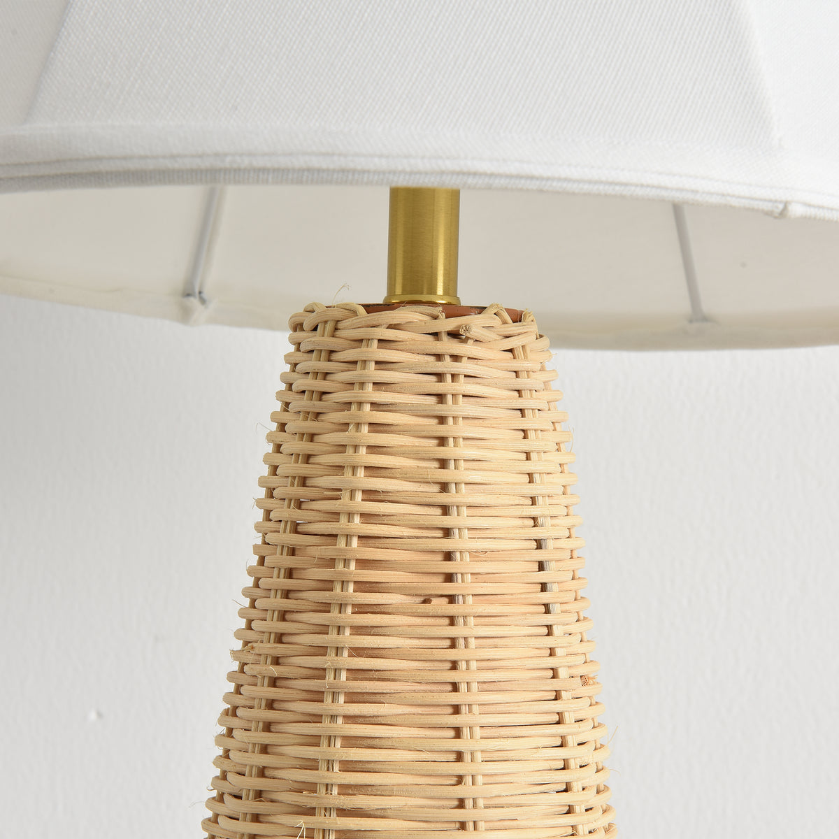Close-up of a table lamp with a woven rattan base and a white fabric shade
