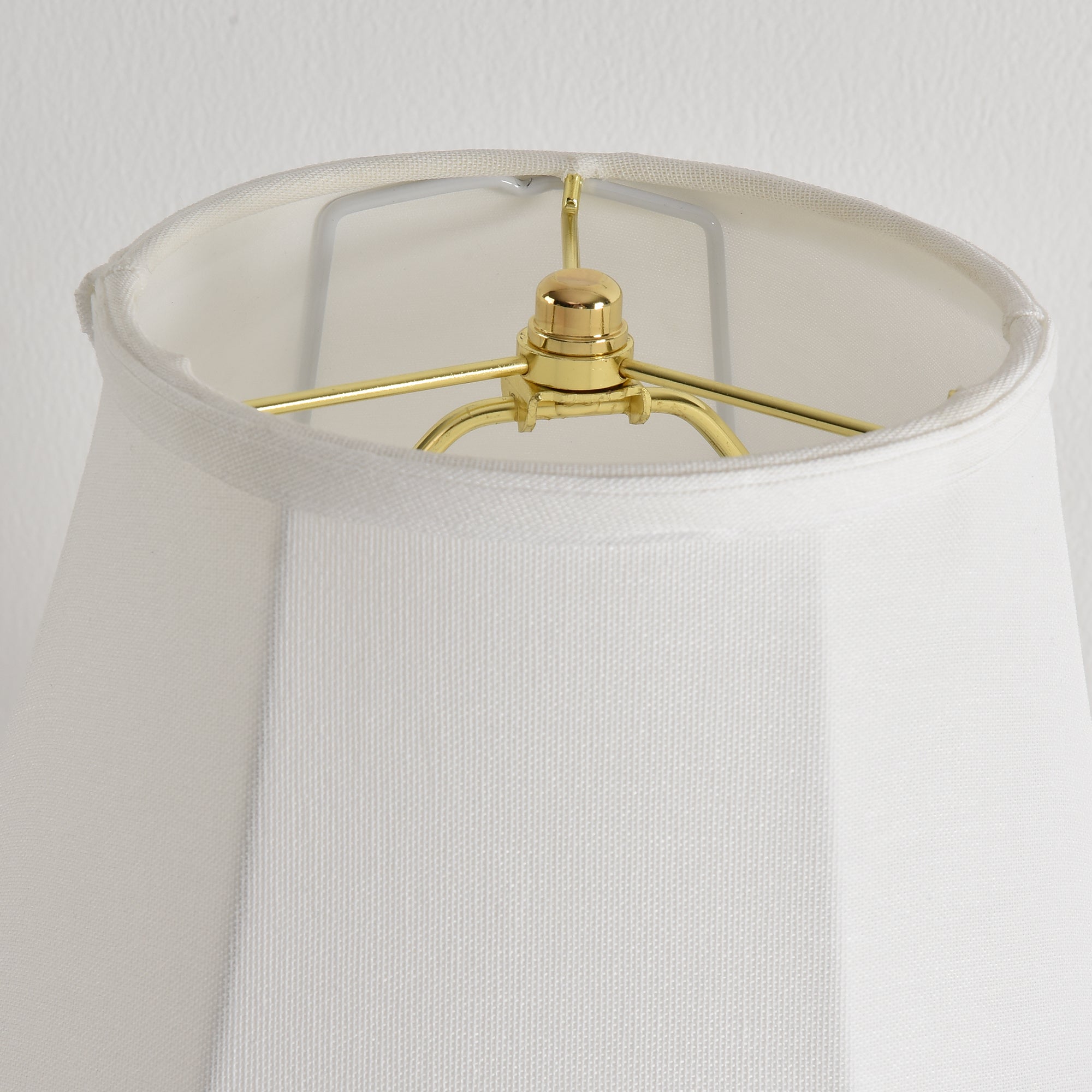 Interior view of a white lampshade showing the gold-toned metal frame and harp.