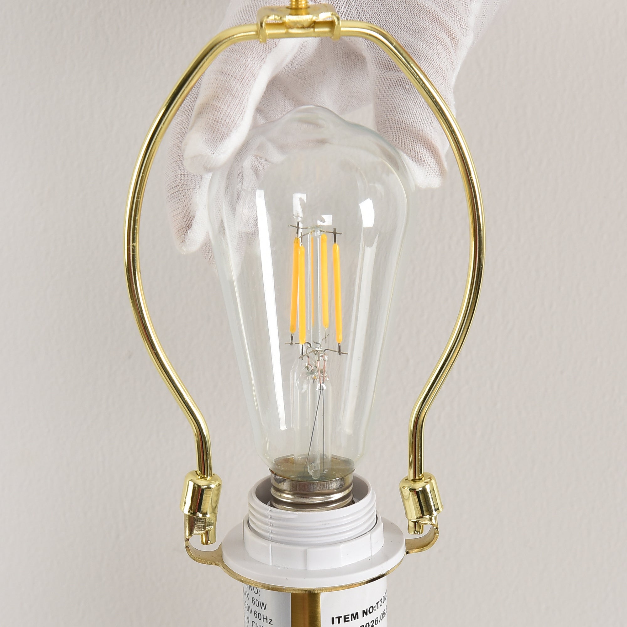 Close-up of a vintage-style LED filament bulb installed in a gold light fixture socket