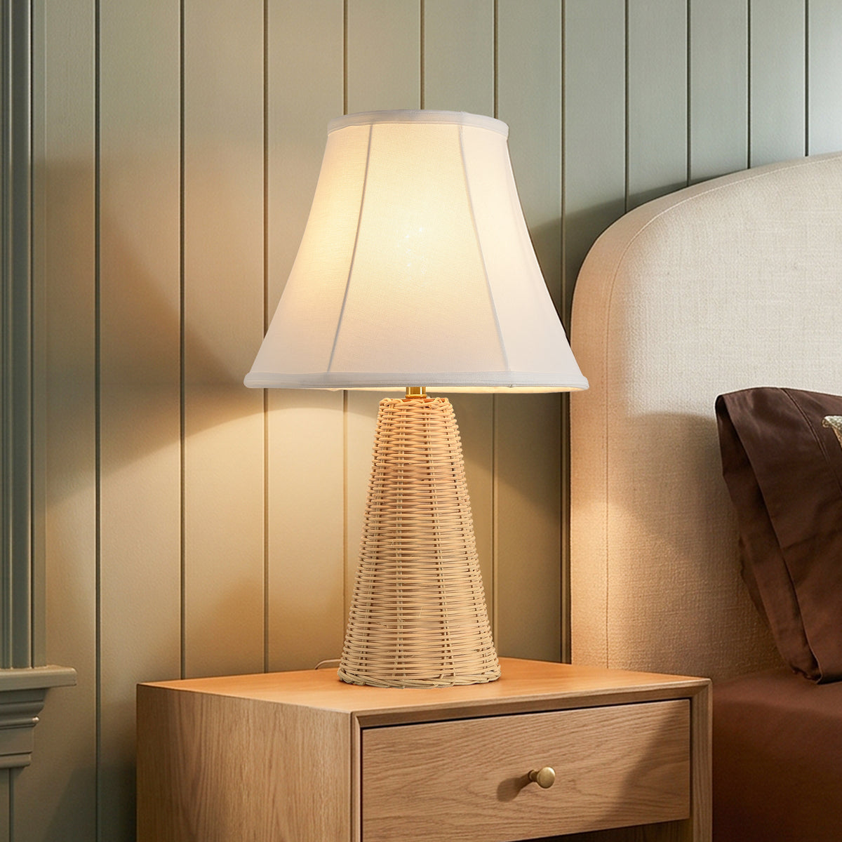 Woven rattan bedside lamp with a white shade on a light wood nightstand