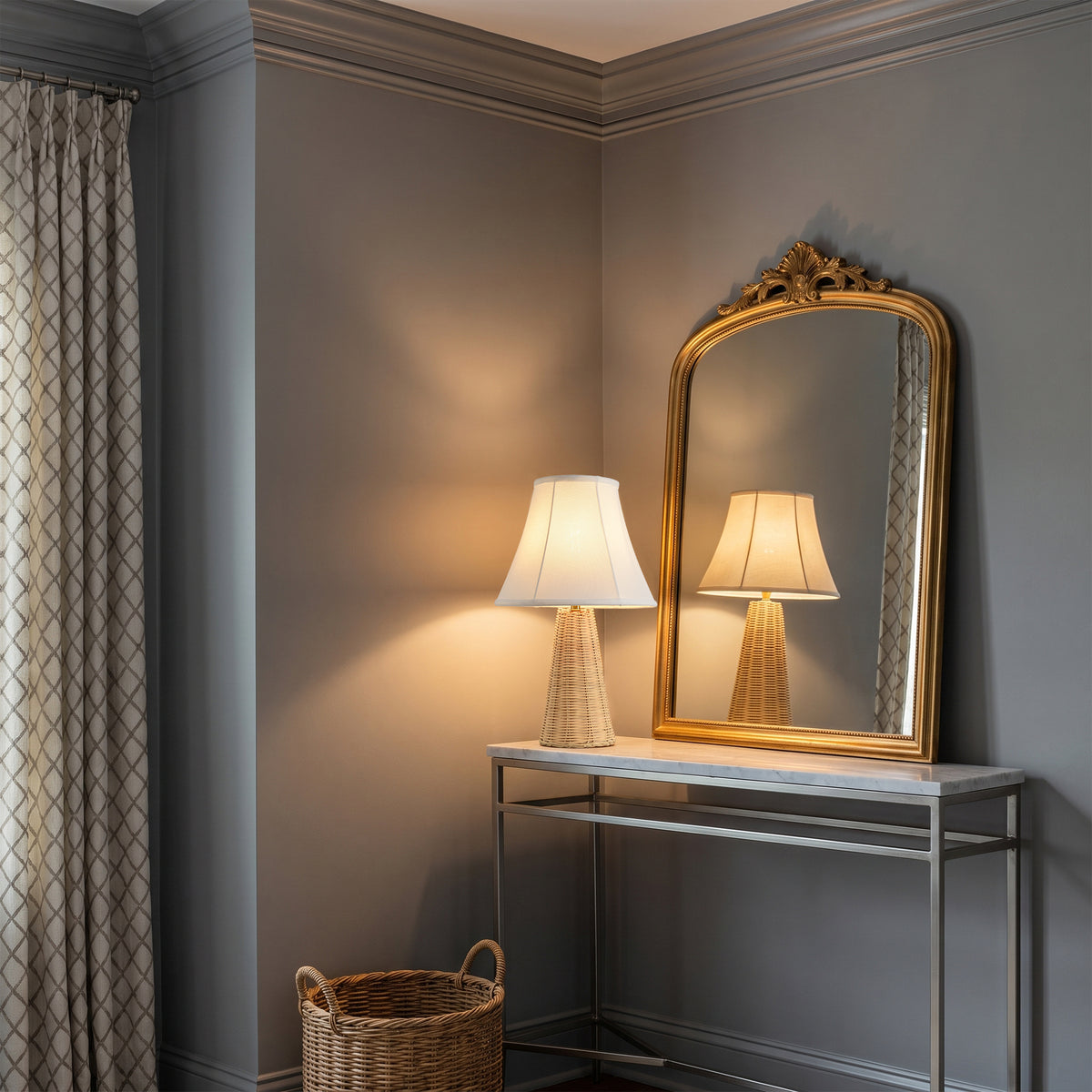Elegant gold-framed mirror and table lamp on a modern console table in a grey room.